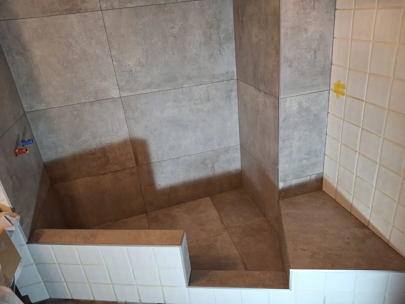 Douche en construction avec carrelage beige et gris